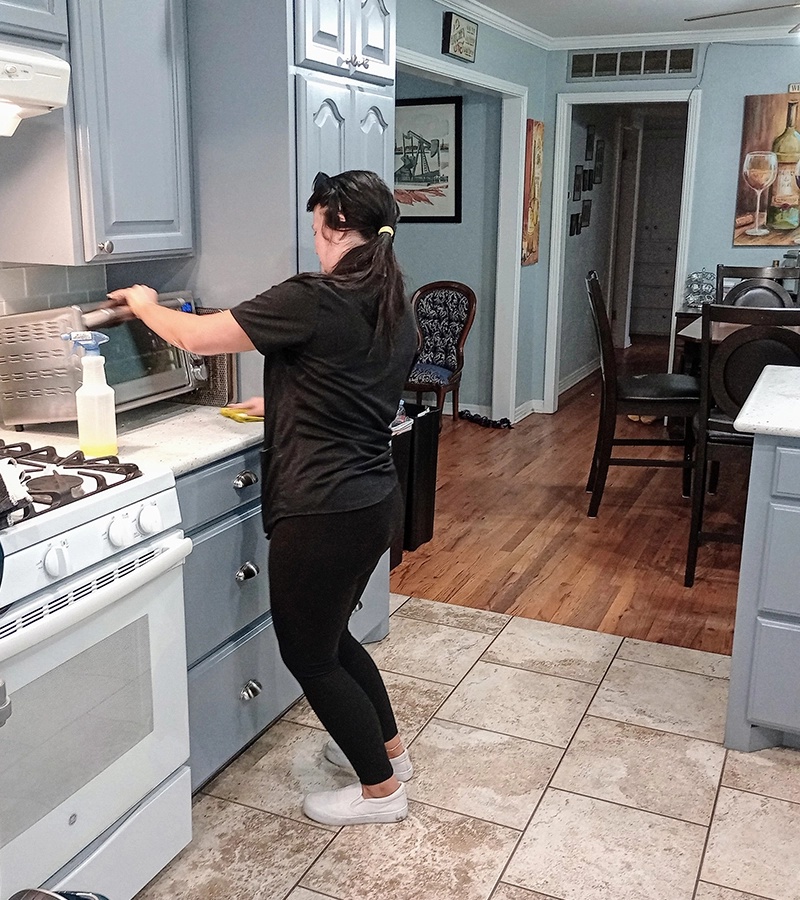 Cleaning under air fryer in kitchen.